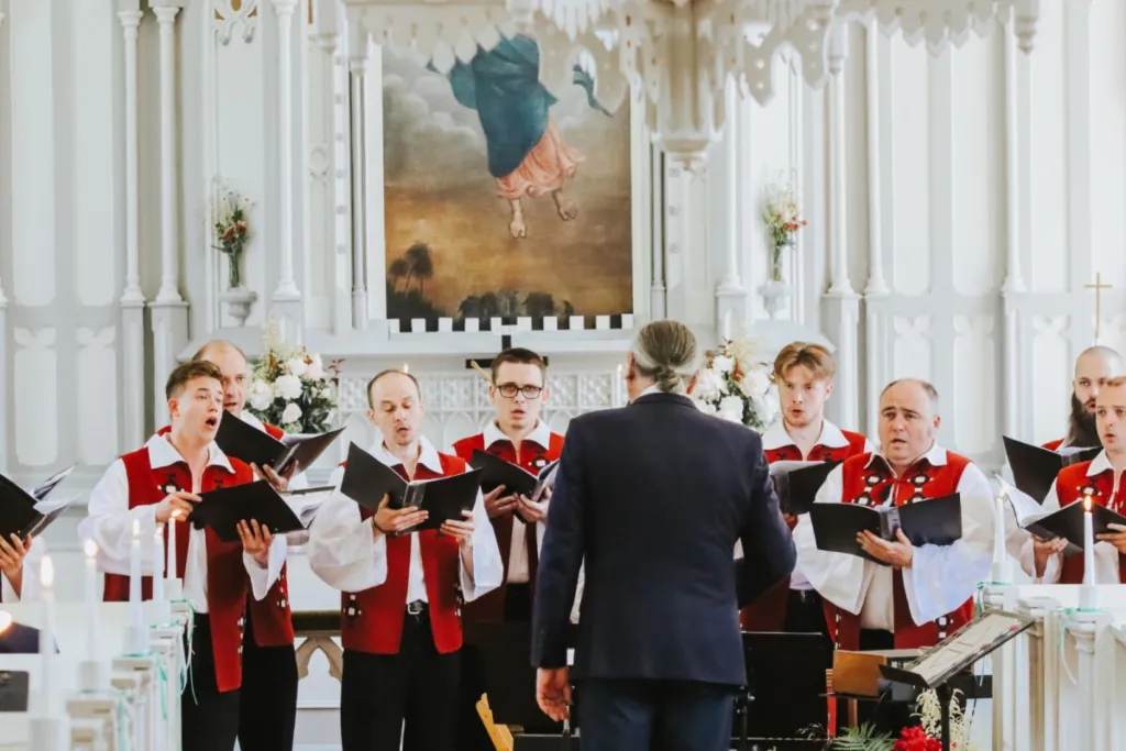 Vīru koris tautastērpos dzied Ziemassvētku koncertā baznīcā